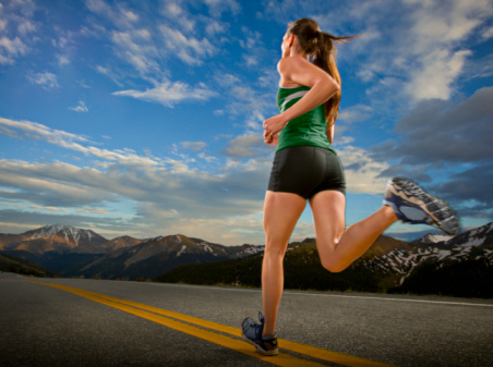 A female road runner runs down a road at dusk at Independence Pass.